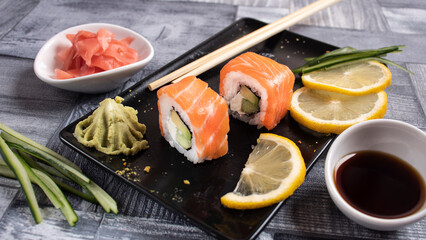 two pieces of sushi on a plate, wasabi, ginger, sticks