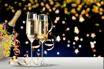 Canvas Print - Glasses and bottle of champagne with serpentine streamers against lights on background.