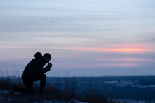 Repentance. A Man On His Knees. Prayer. Silhouette Of A Man On A Blue Sky Background. Kneeling Prayer To God. Glorification. Praising God