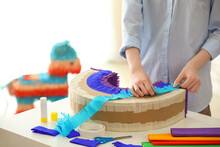 Woman Making Mexican Pinata In Shape Of Rainbow At Table