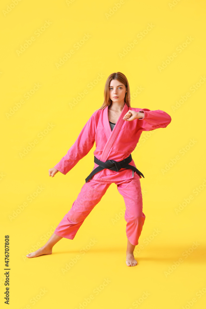 Young woman practicing karate on color background