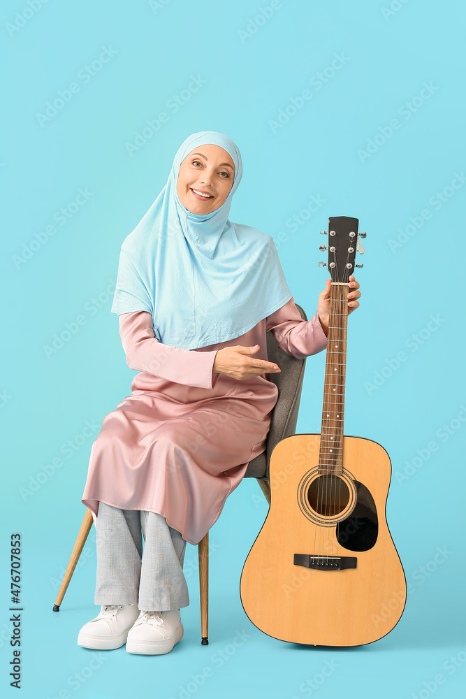 Muslim music teacher with guitar on color background