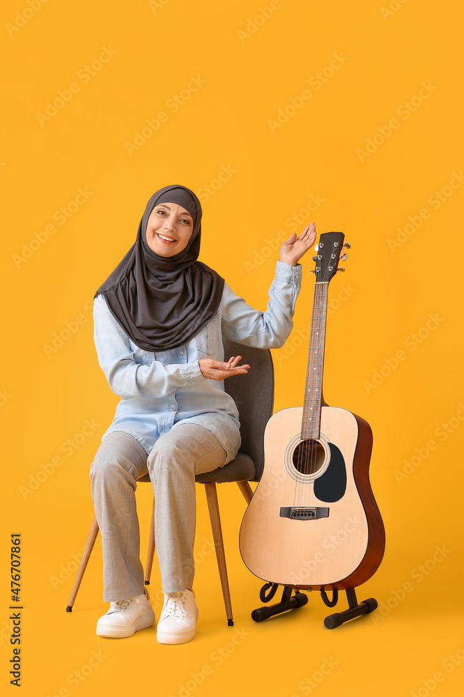Muslim music teacher with guitar on color background