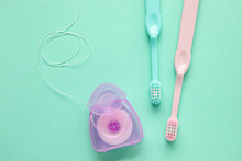 Dental Floss And Toothbrushes On Green Background