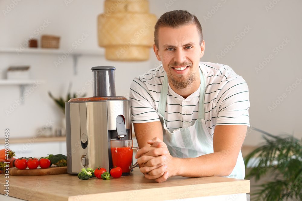 Young man with modern juicer in kitchen