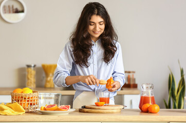 Young woman making fresh citrus juice in kitchen