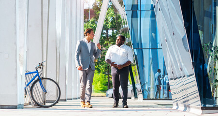 Wall Mural - Finance, business and cooperation concept. Two successful businessmen are talking on the street. Office workers are discussing business issues outdoor.