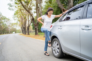 Wall Mural - Young beautiful female using force trying to unscrew the wheel bolts nuts with the car jacked up changing wheel.