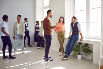 Wall Mural - Diverse international young people talk at break in modern office, chat brainstorm in hallway. Multiracial colleagues coworkers speak chat discuss business project in company. Teamwork concept.