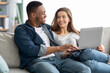 © Prostock-studio - Booking Vacation. Happy Multicultural Couple Using Laptop At Home Together
