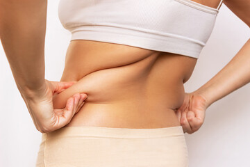 Cropped shot of a young woman holding fat folds on her back isolated on a white background. Overweight, flabby and sagging muscles. Exercises for the back. Body positive