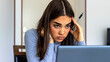 Serious young business woman with a worried expression sitting reading information on her laptop. Shot of a young business woman looking stressed and concerned while using a laptop in her home office.