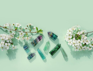 Gemstones minerals set of green colors and white flowers on green background. Healing stones for Crystal Ritual, Esoteric spiritual practice. modern wicca magic. flat lay