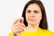 A woman with a disgruntled face holds a pill in her hand. Harm from treatment with medications, distrust of pharmacology