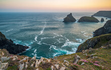 The Coastline Of Cornwall, England. A Summers Evening And The Sky Is Glowing As The Sun Sets Over The Spectacular, Rugged Coastline