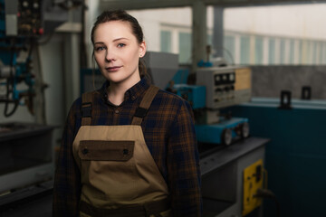 Wall Mural - Young welder in uniform looking at camera in blurred factory