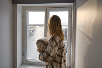 Wall Mural - The girl holds a cozy soft blanket in her hands. Warm blanket in the hands of a woman close-up. Winter mood and home textiles