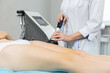 Slender woman receives a cavitation procedure getting anti-cellulite and anti-fat therapy on her tight buttocks in a beauty salon for splitting fat cells under the influence of ultrasound from a