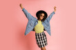 Ecstatic laughing  african woman in black hat and jeans jacket having fun  on pink background in studio.