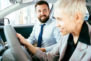 Eco car sale concept, smiling man talking with woman in electric car.