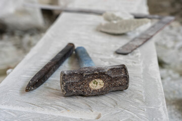 Sculptor tools on a marble slab, close up. Workplace, traditional tools sculptor, red chalk, ruler, hammer and chisel for working stone. Vietnam