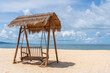 Wooden swing under a thatched roof on a sandy tropical beach near the sea on the island of Phu Quoc, Vietnam