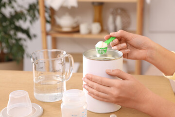 Wall Mural - Woman preparing infant formula at table indoors, closeup. Baby milk