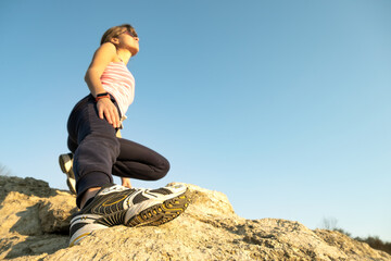 Wall Mural - Woman hiker climbing steep big rock on a sunny day. Young female climber overcomes difficult climbing route. Active recreation in nature concept.