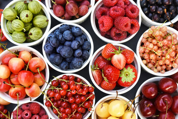 Wall Mural - Fresh ripe organic fruits and berries in bowls from market: strawberry and raspberry, currant and blueberry; healthy fruit and berry background