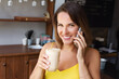 © ksenija1803z - portrait of smiling woman with cup of coffee in her hand and talking o smartphone