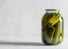 Pickled Cucumbers In A Glass Jar On A Light Background. Homemade Fermented Or Pickled Cucumbers.