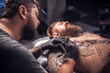 © Mr. Prof - Master of the art of tattooing makes a tattoo on the skin in tattoo parlor