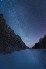 Winter Road In The Forest Under Beautiful Night Sky With Milky Way And Lot Of Stars