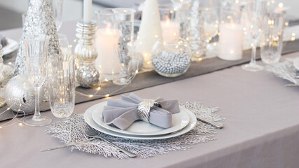 Beautiful table setting with Christmas decorations. Silver colors