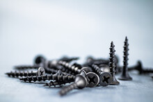 A Bunch Of Self-tapping Screws On The Table. On A Gray Background. High Quality Photo