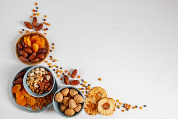 Wall Mural - Mixed nuts and dried fruits on a plate on a white wooden table with copy space.