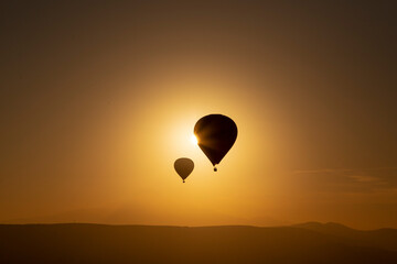 Hot air balloons flying over spectacular Cappadocia. Beautiful view of hot air balloons floating in sunrise blue sky over the mountain landscape of fairy chimneys