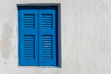 Closed Blue Shutters On A White Wall House In Greece