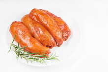 Fresh marinated chicken meat.Raw marinated chicken fillet in red sauce on a white plate on a light background with fresh rosemary leaves and spices.