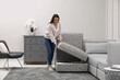 © New Africa - Woman closing modular sofa section with storage in living room