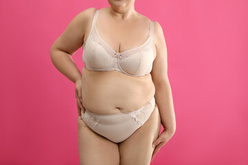 Sticker - Overweight woman in beige underwear on pink background, closeup. Plus-size model