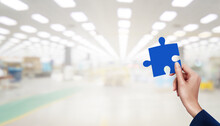 Hand Holding Jigsaw At Factory Building Blur Background.