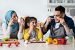 © Prostock-studio - Cheerful islamic family of three having fun while cooking in kitchen together