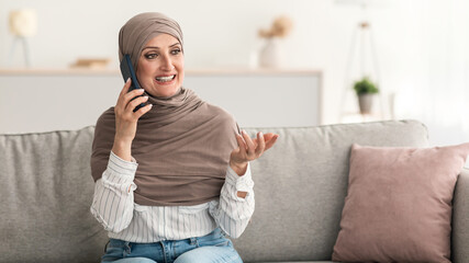 Wall Mural - Senior Islamic Lady Talking On Mobile Phone Sitting At Home