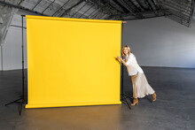 Businesswoman Pointing At Blank Yellow Backdrop