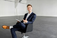 Young Businessman With Tablet PC On Chair At Industial Hall
