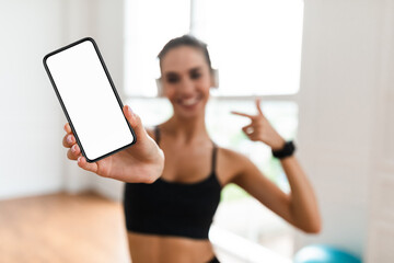 Wall Mural - Happy sporty woman showing phone with blank screen