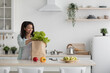 © Prostock-studio - Fresh organic vegetables, greens and fruits in eco brown paper bag on white table in kitchen