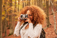 Woman With Brown Curly Hair Photographing In Autumn Forest