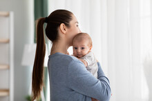 Maternal Mental Health Problems. Young Woman Holding Newborn Baby Standing Near Window